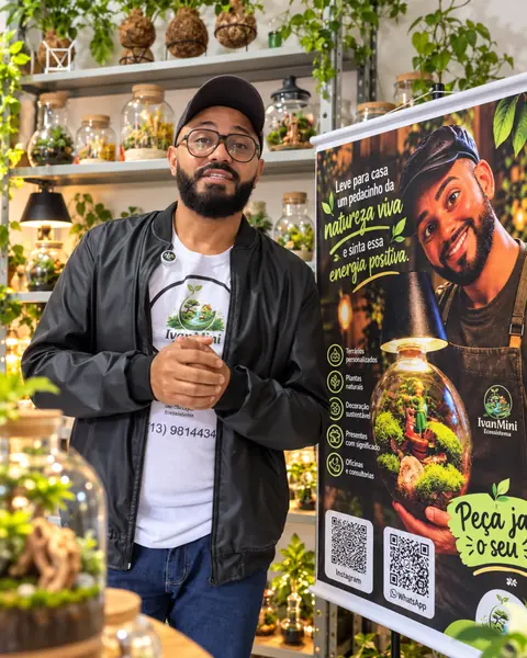 Ivan ao lado do banner da marca e das prateleiras de terrários