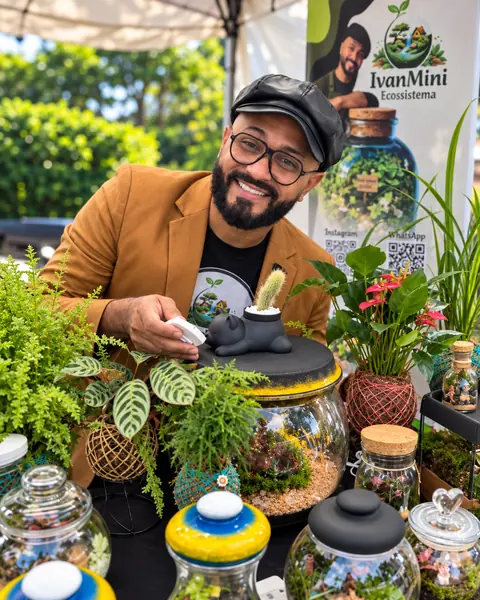 Ivan finalizando um terrário com tampa de gatinho numa exposição ao ar livre